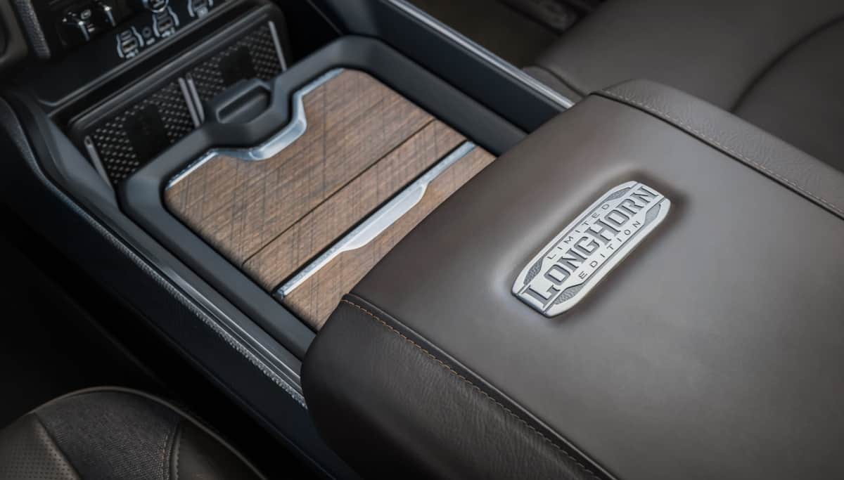 Display The dual charging pads, covered storage and branded armrest in the center console of the 2026 Ram 3500 Limited Longhorn.