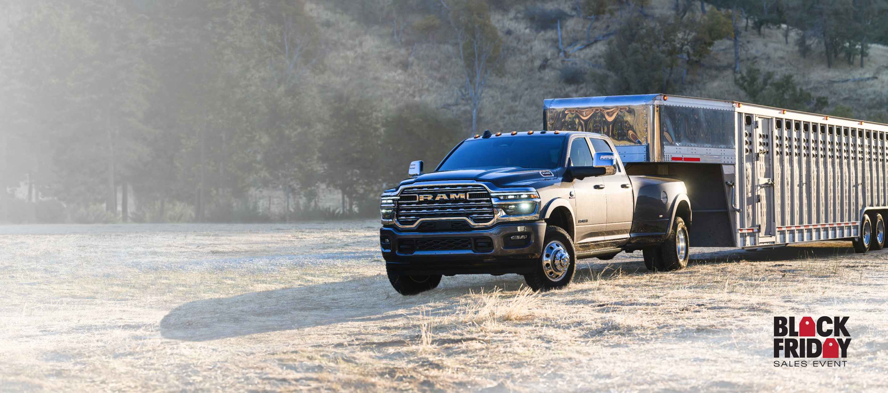 A gray 2026 Ram 3500 Limited Longhorn 4x4 Crew Cab towing a large fifth-wheel livestock trailer as it travels off-road. Black Friday Sales Event.