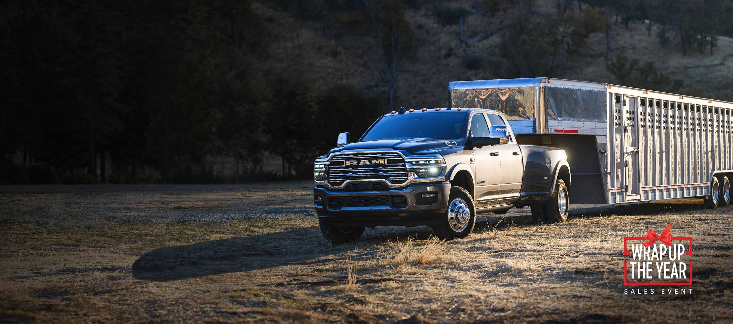 A gray 2026 Ram 3500 Limited Longhorn 4x4 Crew Cab towing a large fifth-wheel livestock trailer. Wrap Up The Year Sales Event.