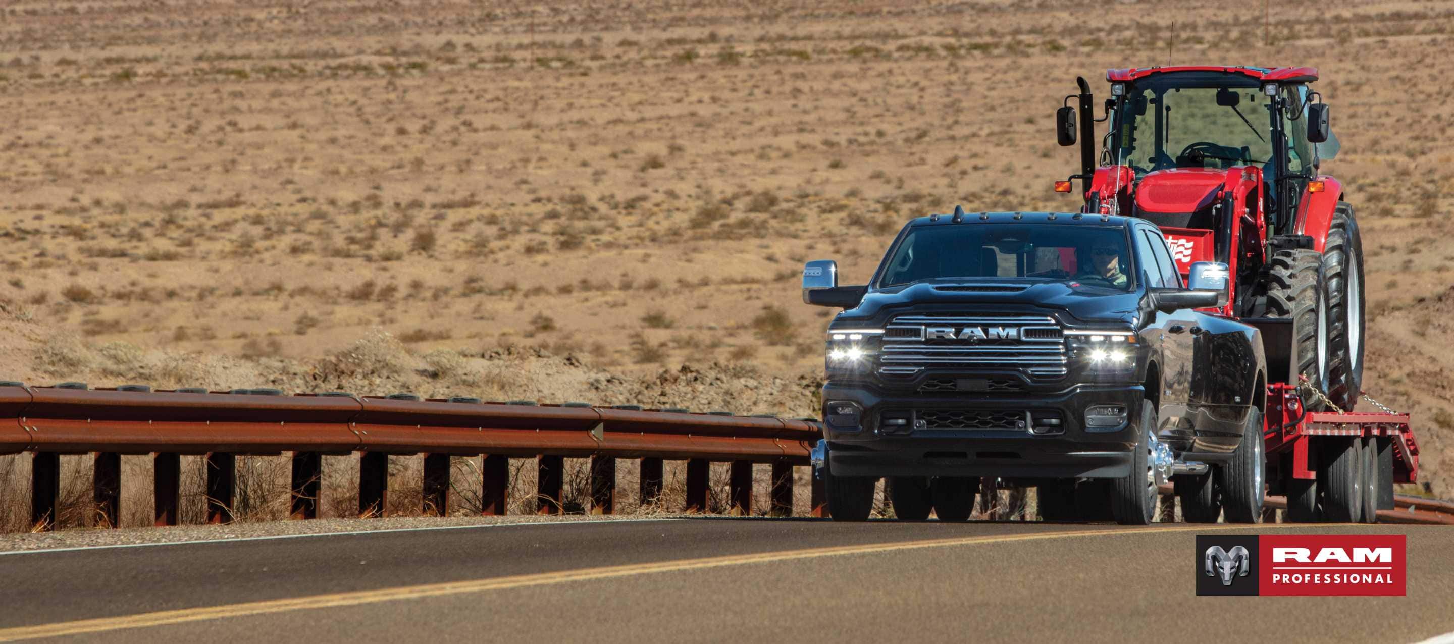 Display A black 2026 Ram 3500 Limited Longhorn 4x4 Crew Cab towing a construction vehicle on a long flatbed trailer as it travels on a mountain road. Ram Professional