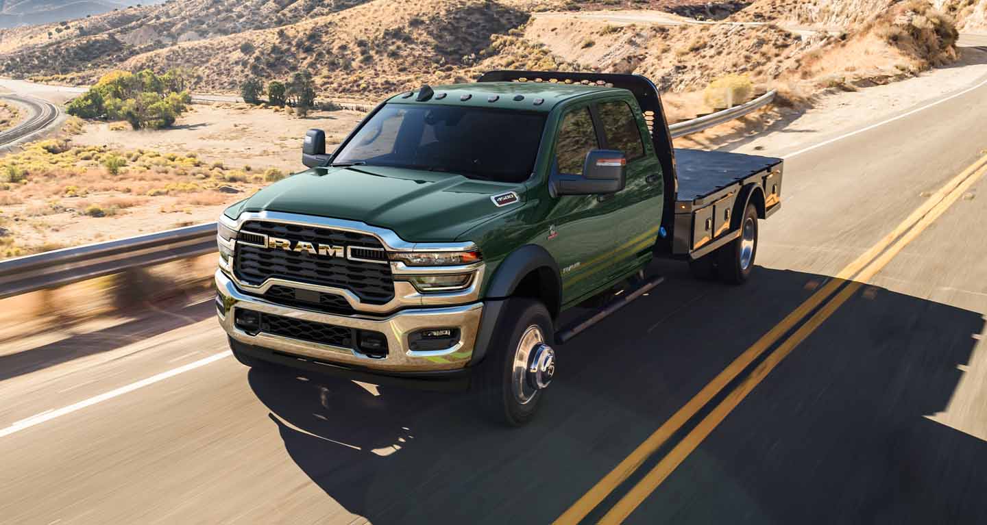 Display A green 2026 Ram 4500 Big Horn 4x2 Chassis Cab Crew Cab with a platform upfit, traveling down a highway.