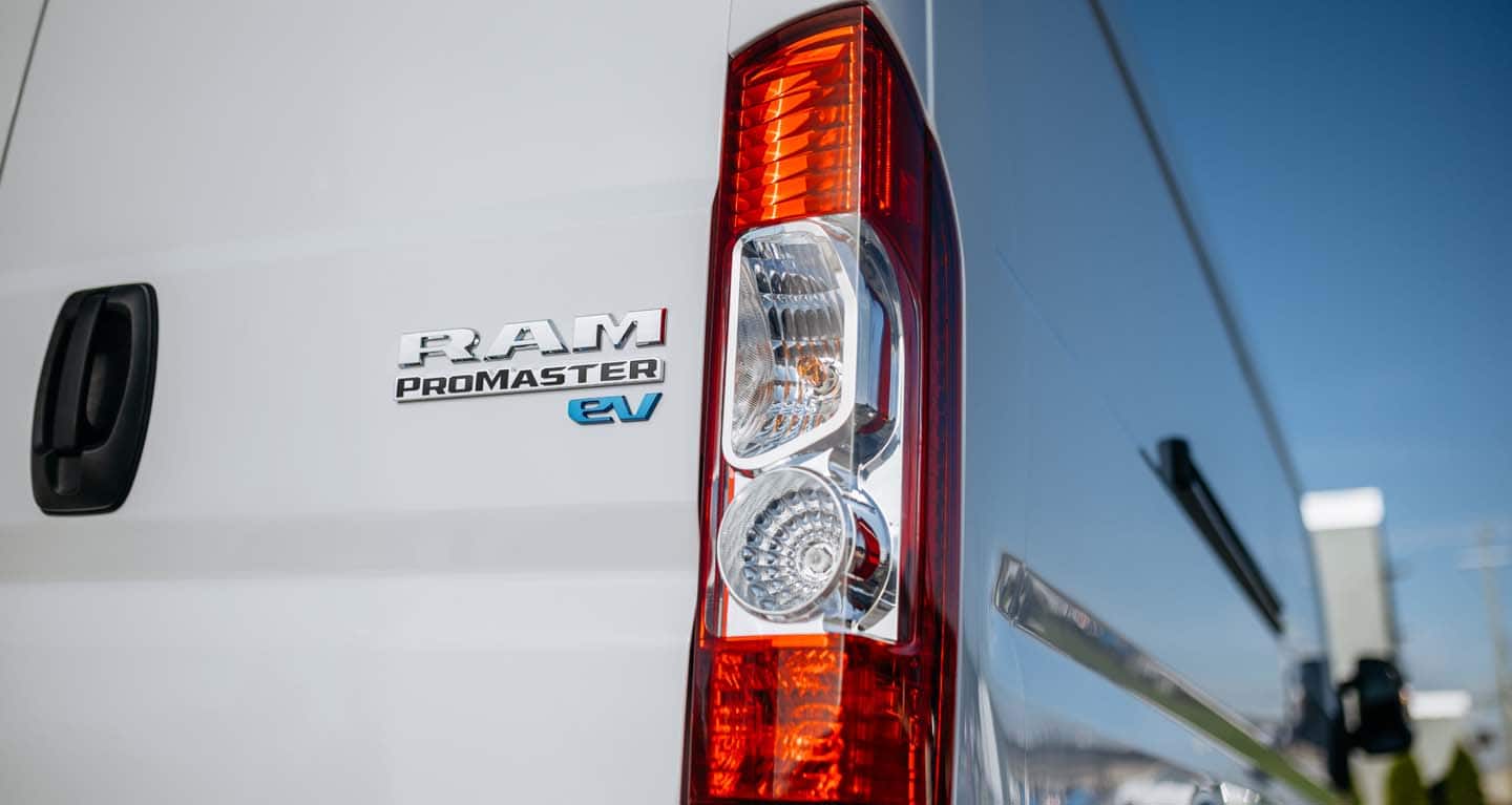Display The Ram ProMaster EV badge and passenger-side taillamp on a white 2026 Ram ProMaster EV 3500 High Roof Cargo Van.