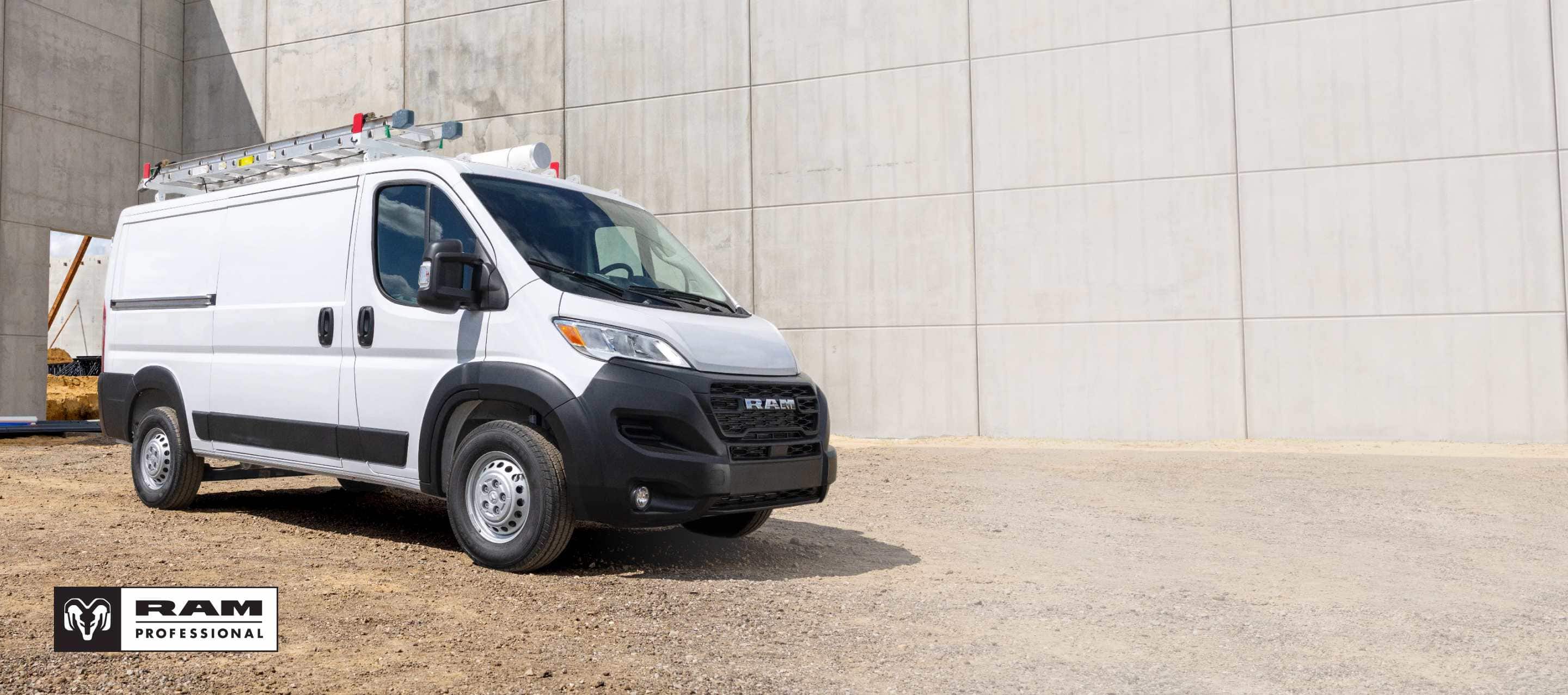 A white 2026 Ram ProMaster Tradesman Standard Roof Cargo Van with a ladder on its roof rack, at a construction site, shot on an angled profile. Ram Professional.