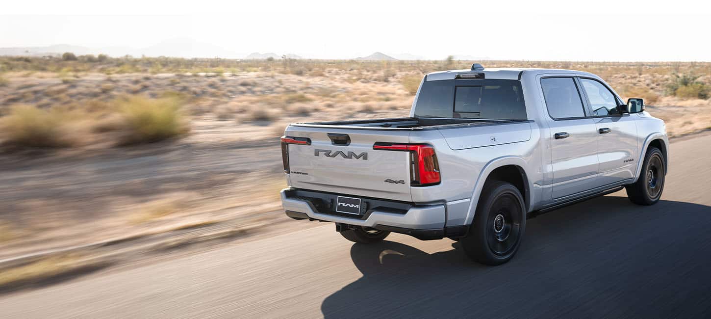 Silver Ram 1500 REV driving, rear three-quarter view