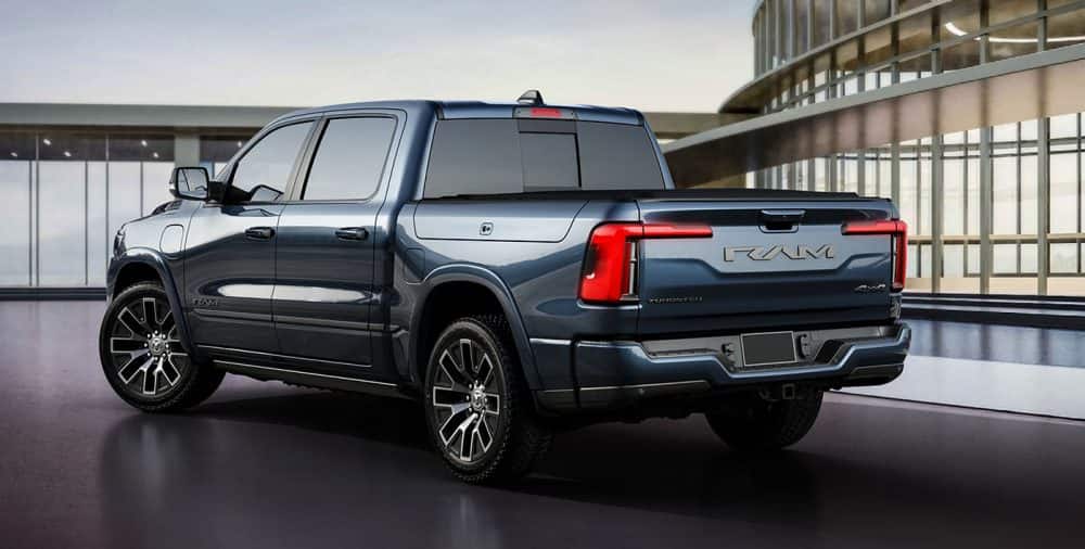 Dark blue Ram 1500 REV parked by a modern building, rear three-quarter view