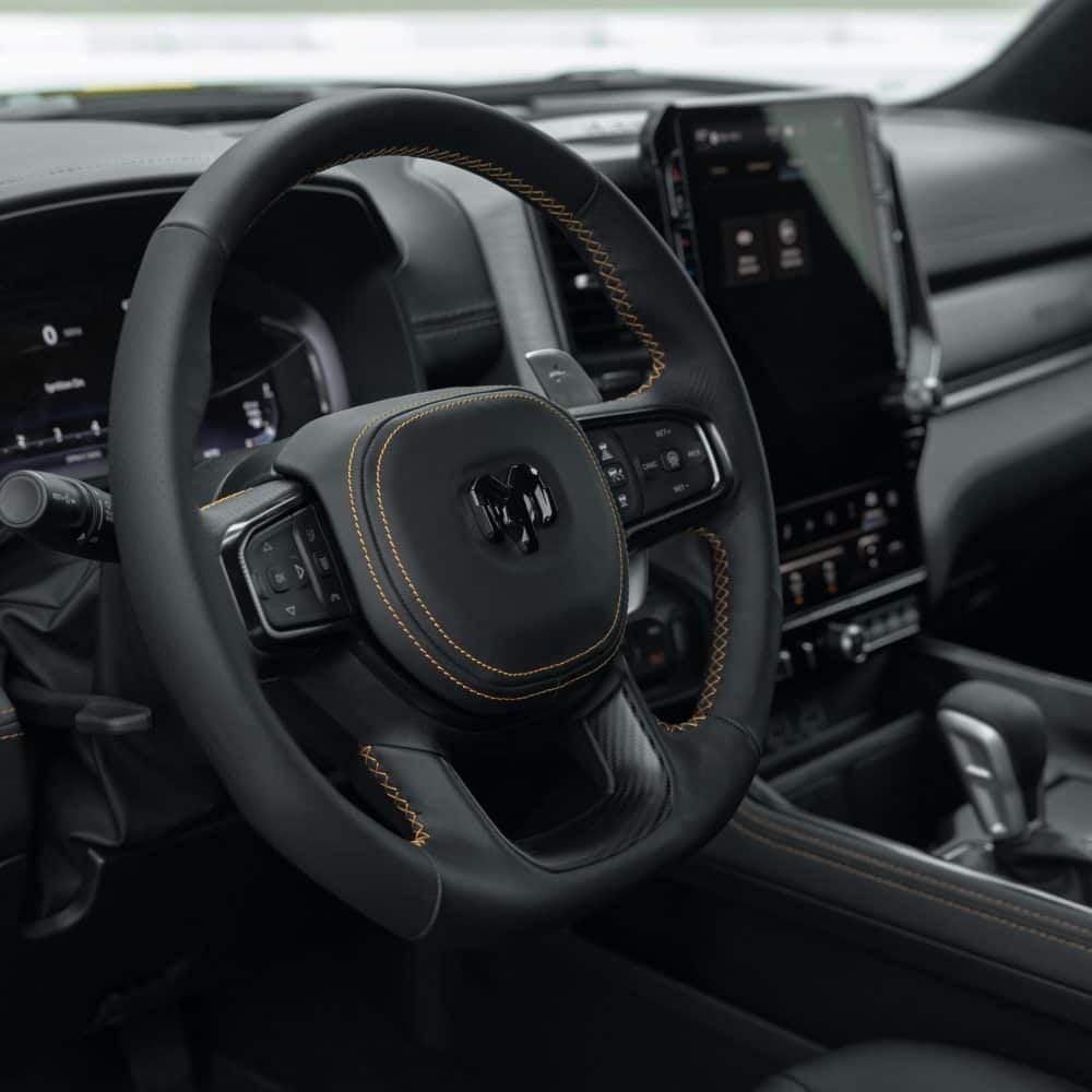 Ram 1500 Rumble Bee cockpit with a flat-bottom steering wheel, paddle shifters and a large touchscreen