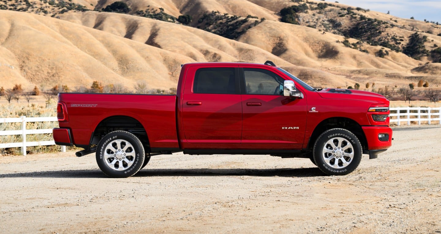 A red 2027 Ram 2500 Sport parked on a dirt road with hills in the background