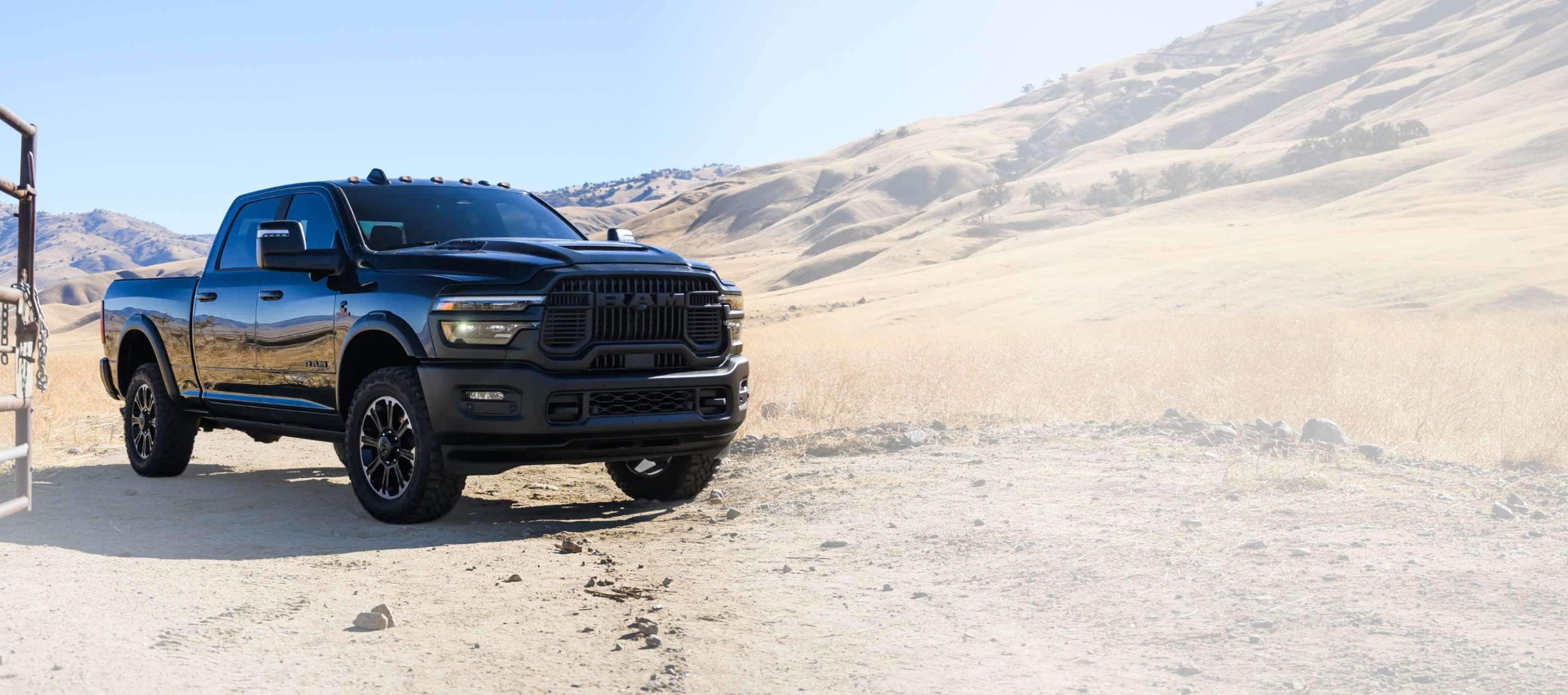 A black 2027 Ram 2500 Heavy Duty Rebel Crew Cab pickup truck at a ranch in the desert. Rugged By Nature.