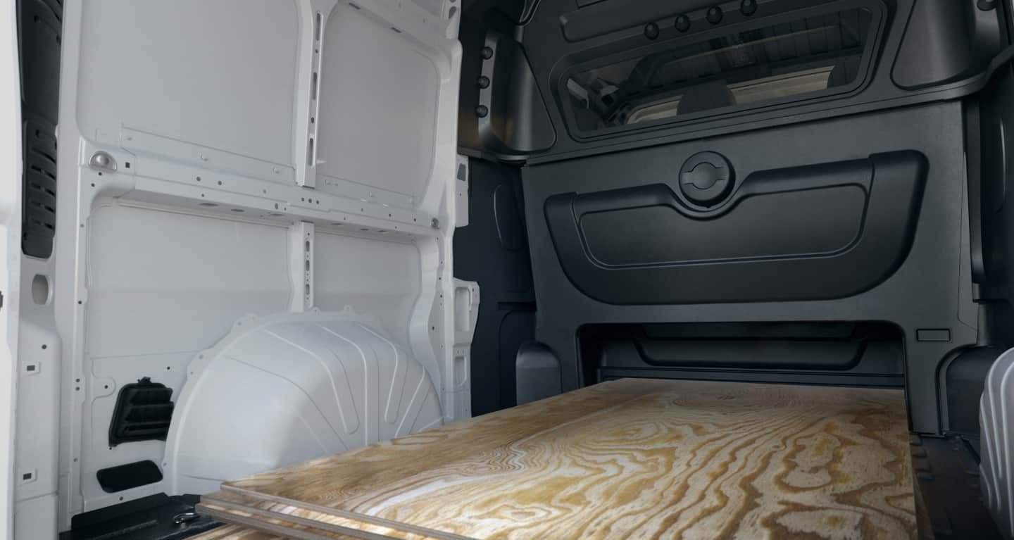 Display The rear of the 2027 Ram ProMaster Cargo Van High Roof with the Crew Van Package, displaying the large cargo area, the partition between the rear seats and cargo area and the six inches of extra height under the rear seat.