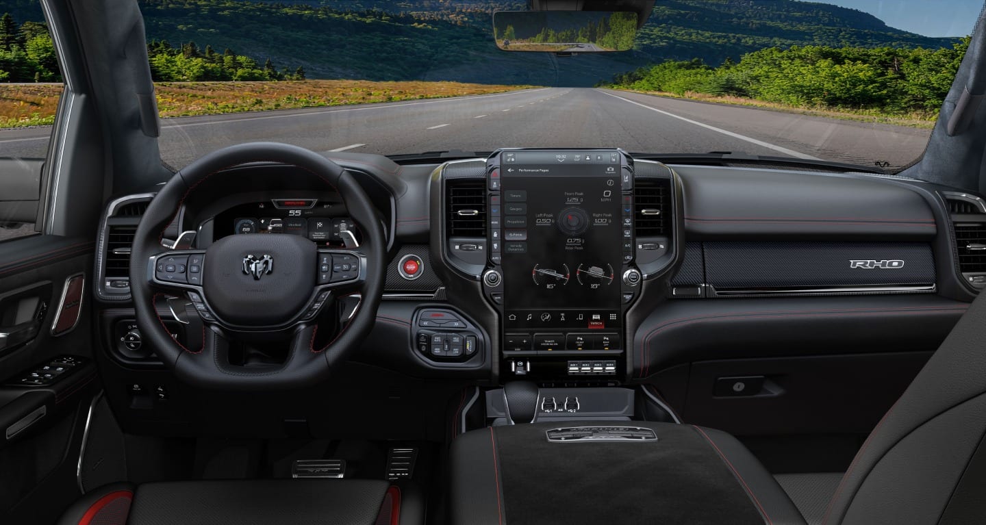 Display The interior of the 2027 Ram 1500 RHO 4x4 Crew Cab, focusing on the steering wheel, Digital Cluster Display, Uconnect touchscreen and center stack controls.