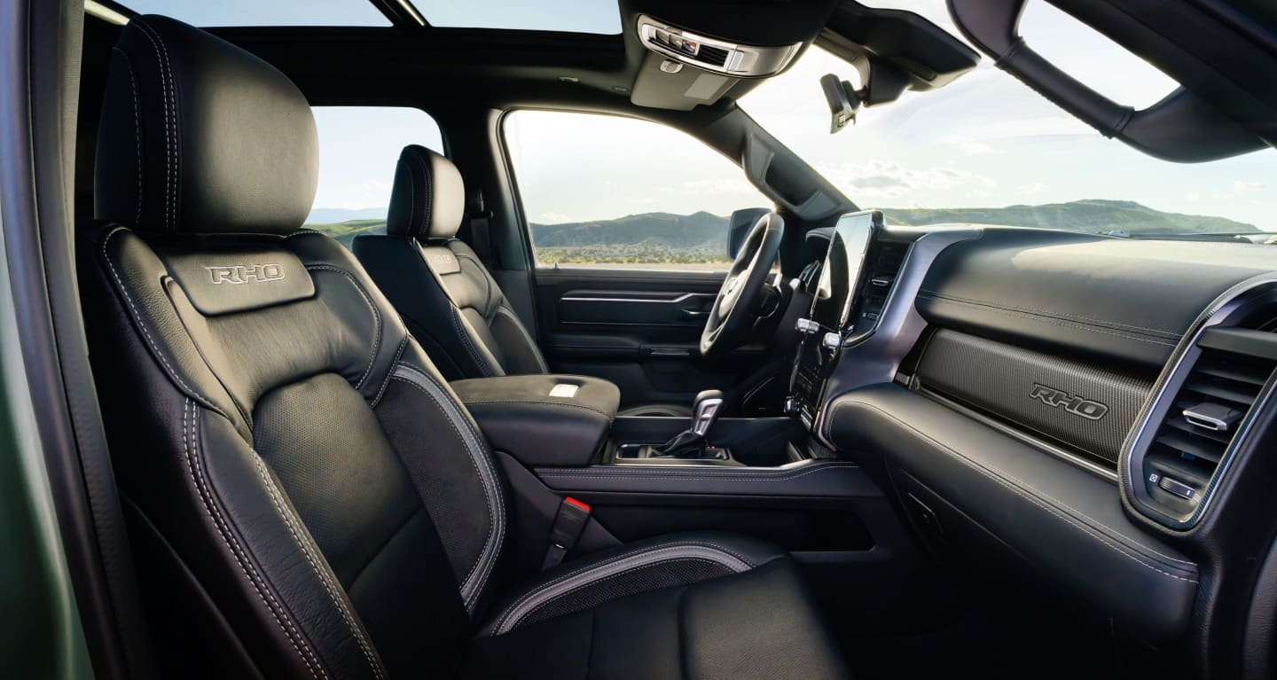 Display The front row of the 2027 Ram 1500 RHO 4x4 Crew Cab with the sunroof open, shot from the passenger side.