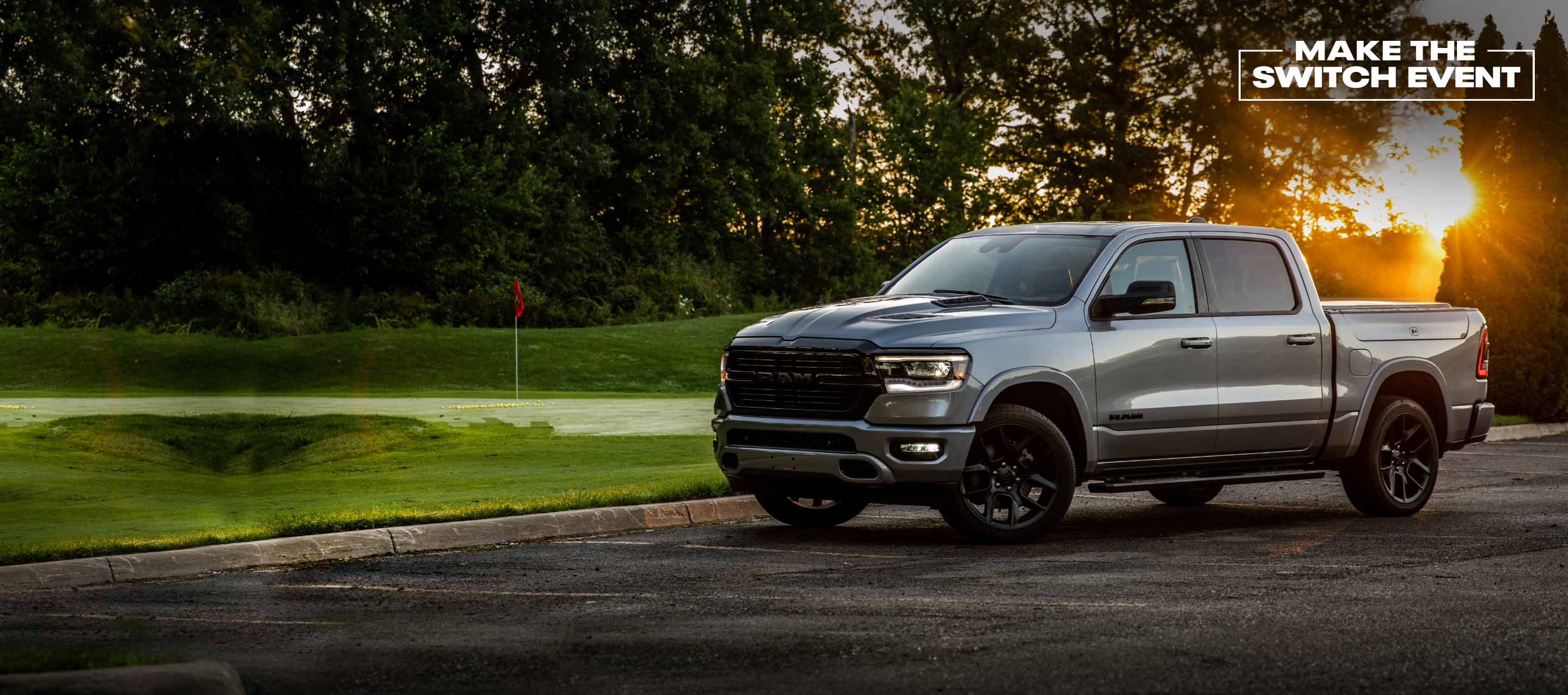A 2022 Ram 1500 Laramie parked beside a golf course. Make the Switch Event logo.