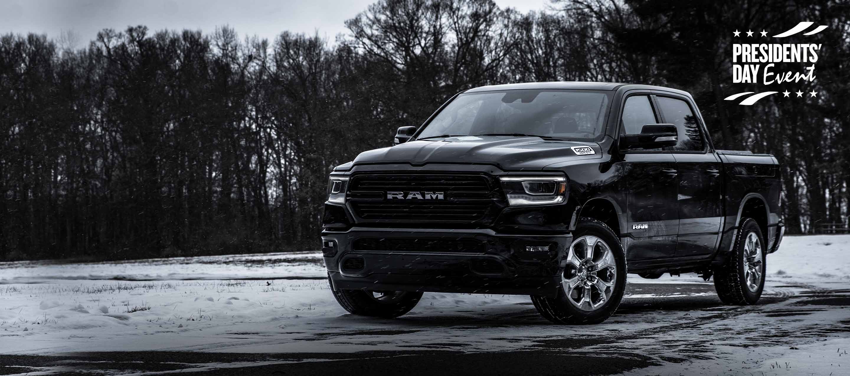 A 2022 Ram 1500 Big Horn 4x4 parked on a snow-covered clearing in the woods. The Presidents' Day Event logo.