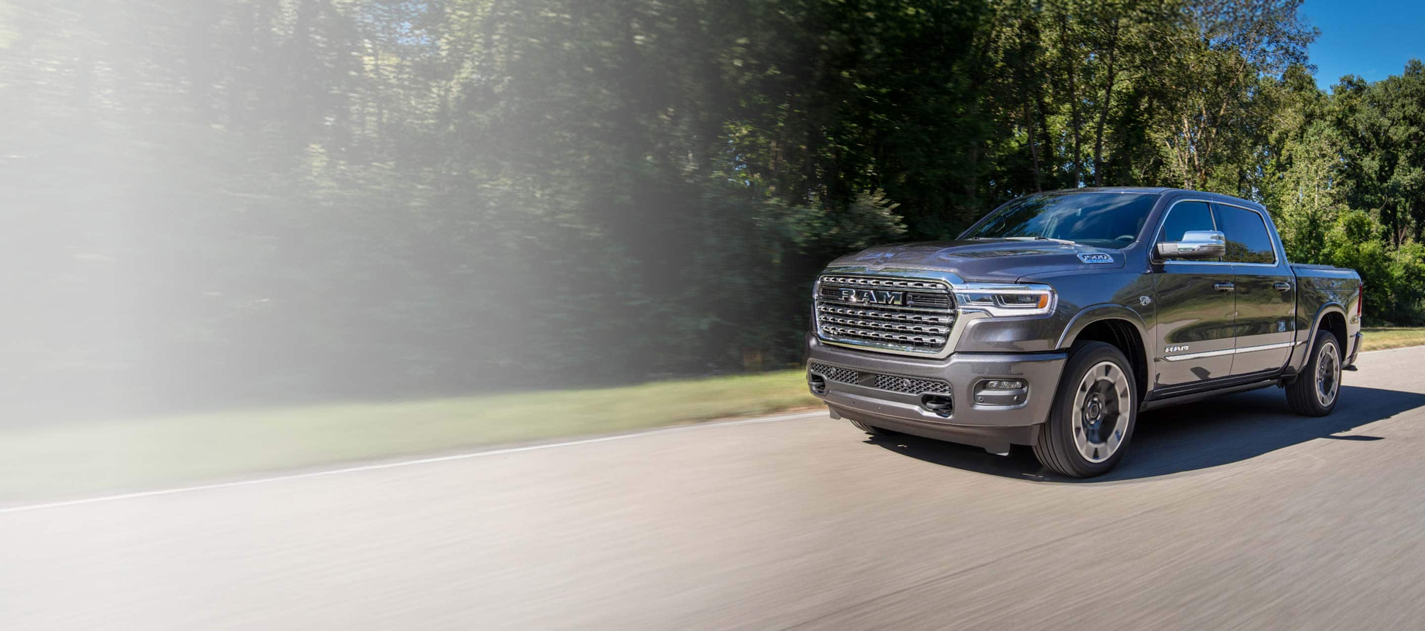 A gray 2026 Ram 1500 Limited 4x4 Crew Cab traveling down a country road.