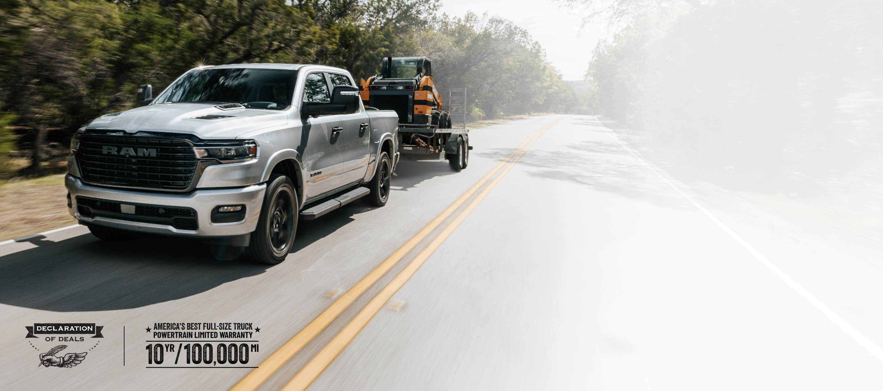A silver 2026 Ram 1500 Laramie 4x4 Crew Cab traveling down a highway, towing a skidsteer loader. Limited Warranty—10 Years/100,000 Miles. Declaration  of deals Sales Event.
