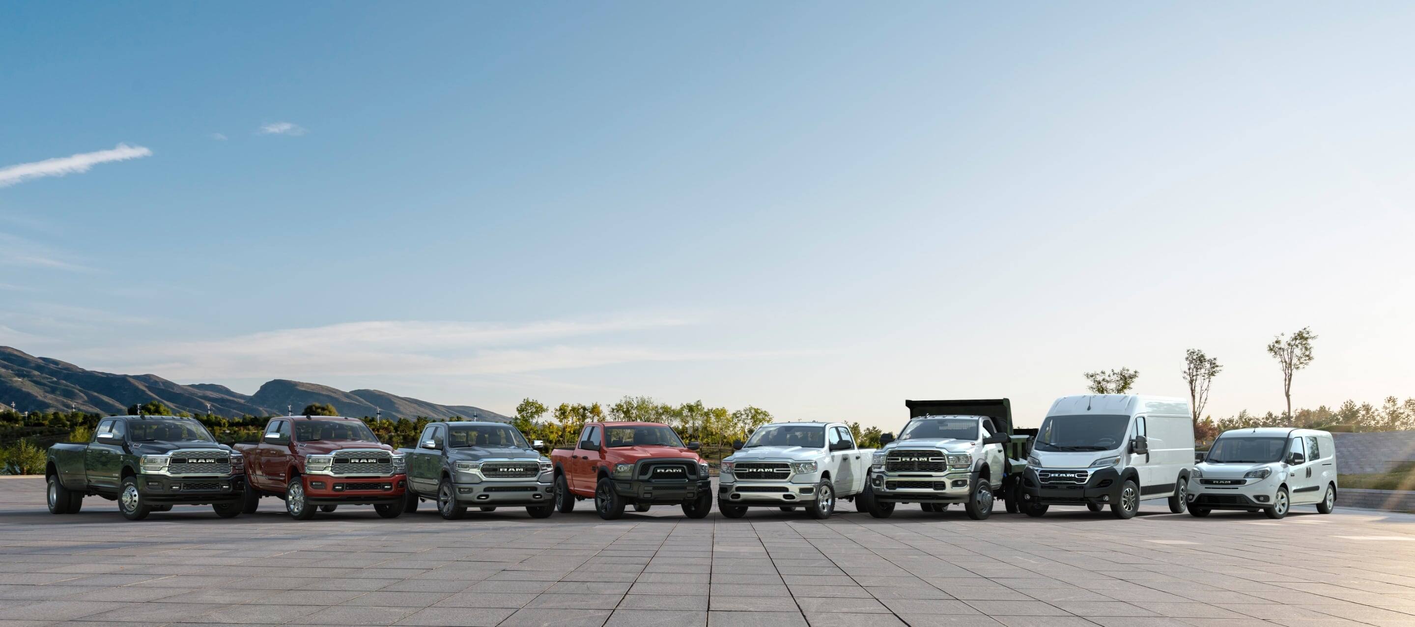 A lineup of six 2022 Ram trucks and two Ram vans parked in a semicircle. From left to right: Three Ram Limited 4x4 Crew Cabs – a 3500, 2500 and 1500 followed by a Ram 1500 Classic Warlock 4x4 Quad Cab, Ram 1500 Tradesman 4x4 Crew Cab, Ram 5500 Tradesman Chassis Cab 4x2 with Dump Body, 2023 Ram ProMaster Cargo Van High Roof and 2022 Ram ProMaster City Wagon. 