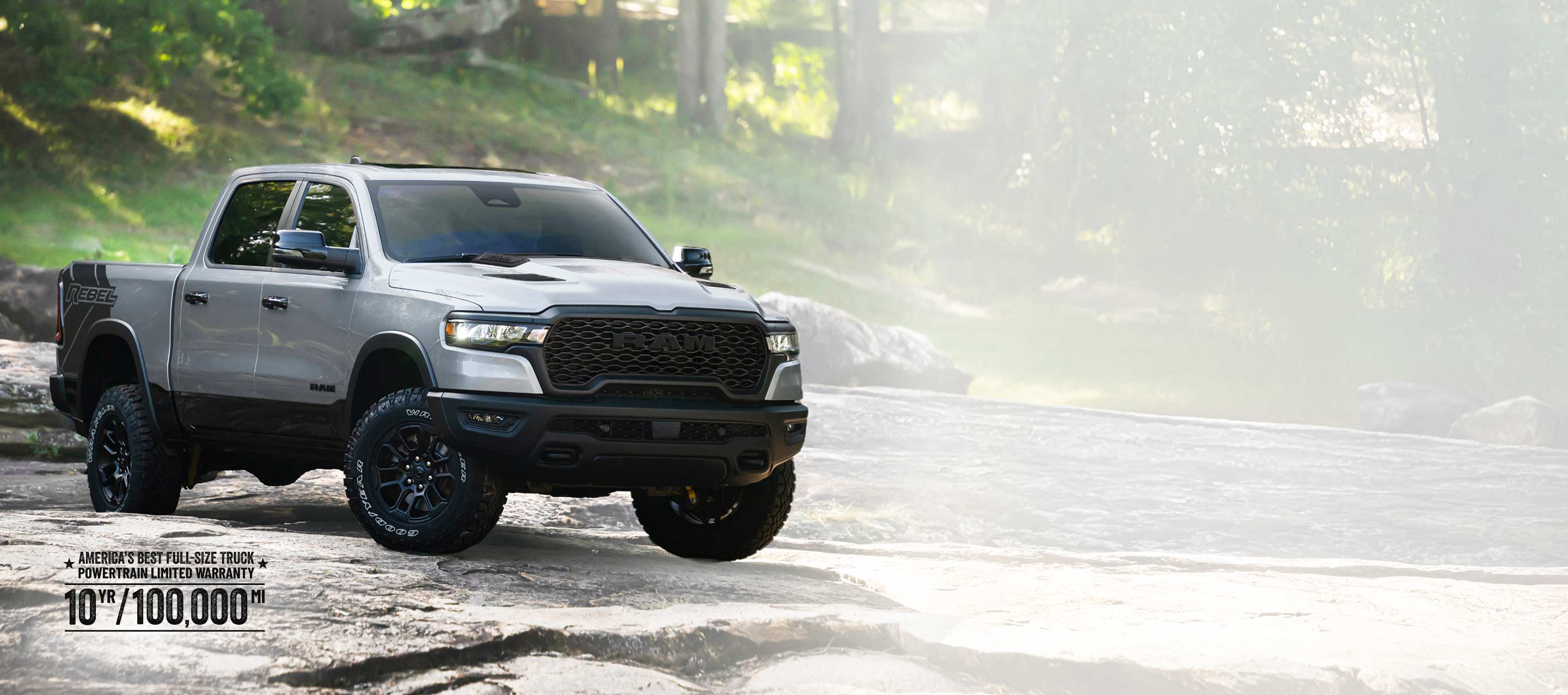 A silver 2026 Ram 1500 Rebel 4x4 Crew Cab traveling across an uneven trail off-road. Wrap Up The Year Sales Event.