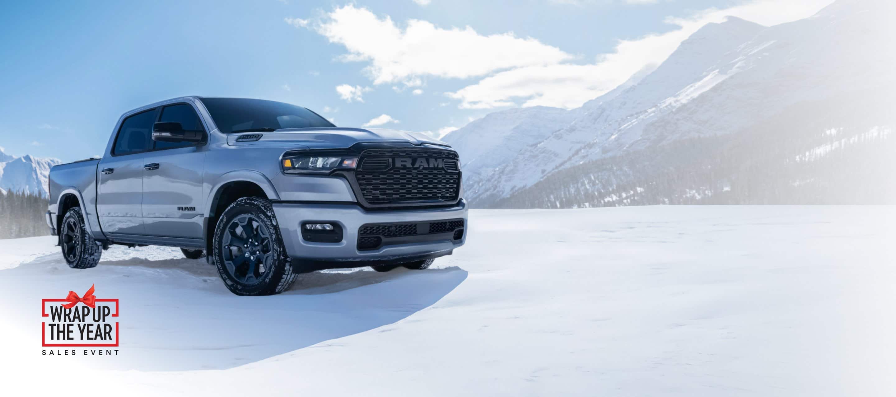 A white 2026 Ram 1500 Big Horn 4x4 Crew Cab parked on a snow-covered clearing off-road in the mountains. Limited warranty 10yr/ 100,000mi.