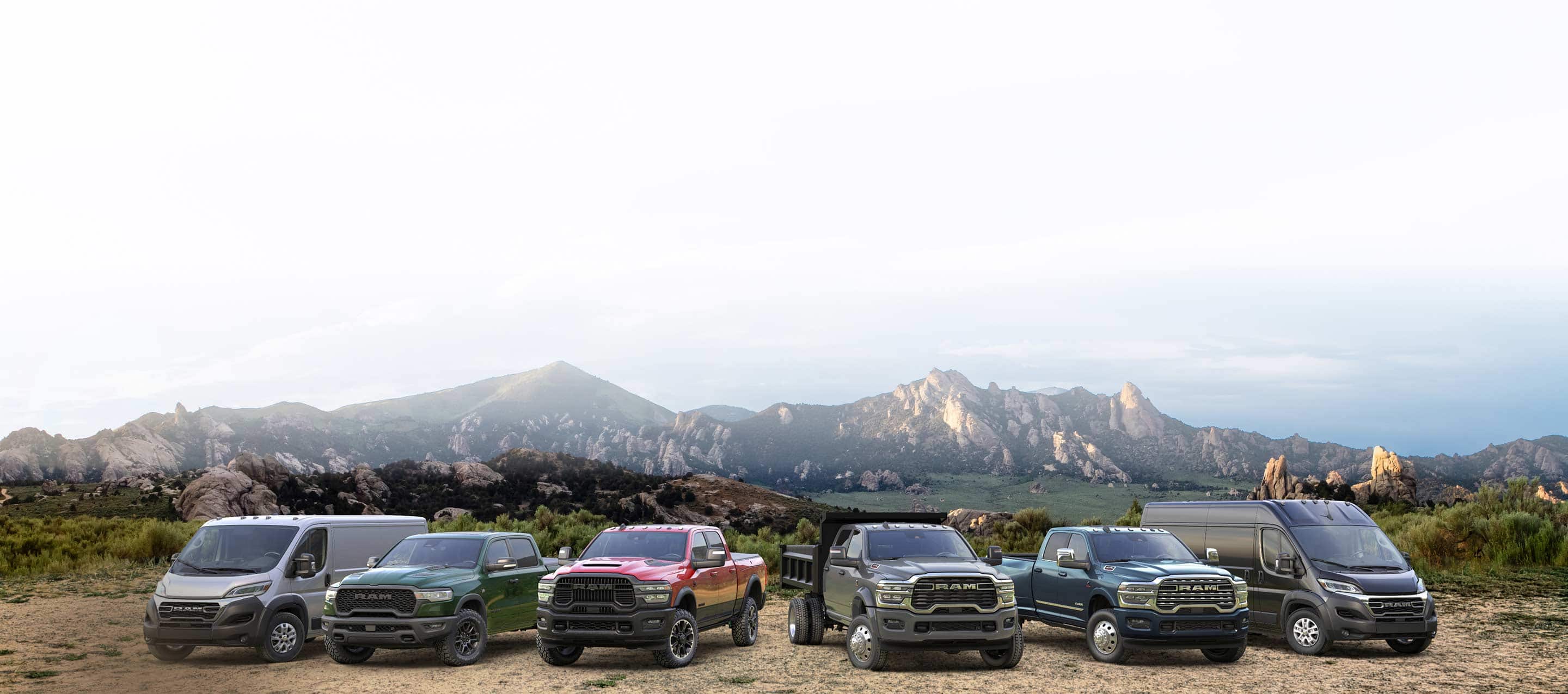 The 2026 Ram lineup: a white Ram ProMaster 2500 SLT Standard Roof Cargo Van, a green Ram 1500 Rebel 4x4 Crew Cab, a red Ram 2500 Rebel 4x4 Crew Cab, a gray Ram 4500 Big Horn Chassis Cab Crew Cab with dump body upfit, a blue Ram 3500 Limited 4x4 Crew Cab and a black Ram ProMaster 3500 SLT Plus High Roof Cargo Van, all parked side-by-side on a hilltop.