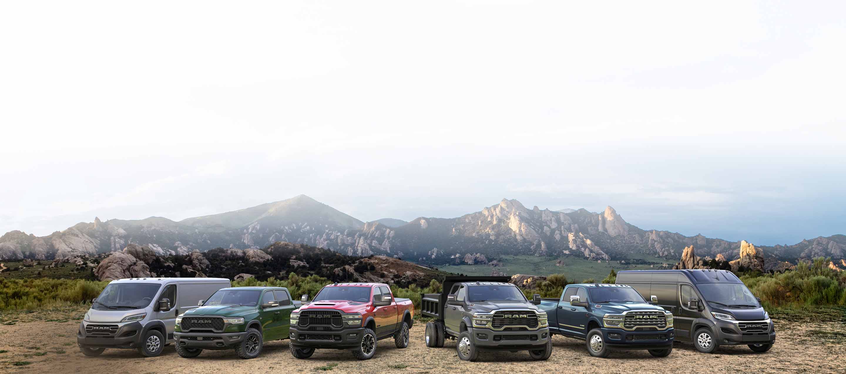 The 2026 Ram lineup: a white Ram ProMaster 2500 SLT Standard Roof Cargo Van, a green Ram 1500 Rebel 4x4 Crew Cab, a red Ram 2500 Rebel 4x4 Crew Cab, a gray Ram 4500 Big Horn Chassis Cab Crew Cab with dump body upfit, a blue Ram 3500 Limited 4x4 Crew Cab and a black Ram ProMaster 3500 SLT Plus High Roof Cargo Van, all parked side-by-side on a hilltop.