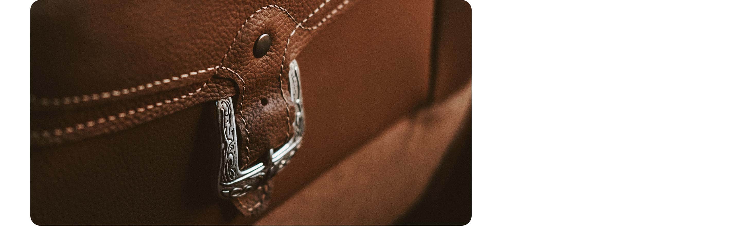 A close-up of the silver-toned buckle accent on the mountain brown front seat back pocket in the 2021 Ram 1500 Limited Longhorn 10th Anniversary Edition.