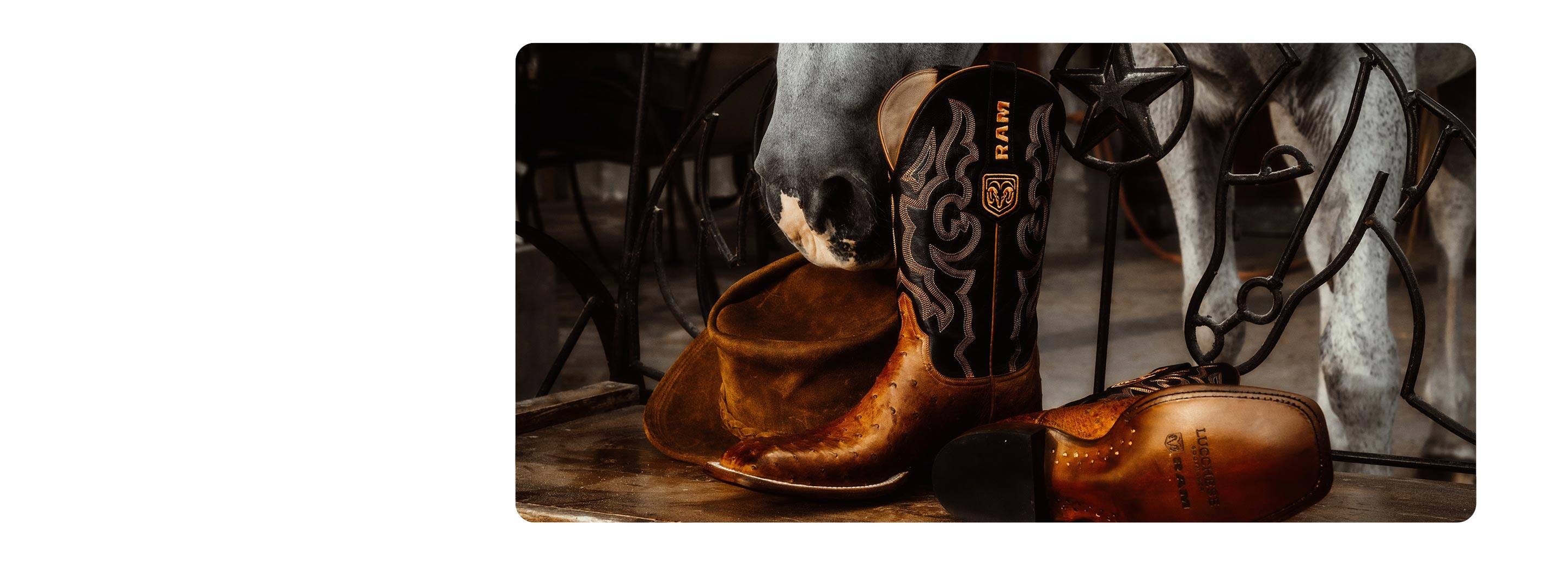 Close-up on an elaborately tooled leather cowboy boot, emblazoned with a Ram's Head logo and Ram brand mark.