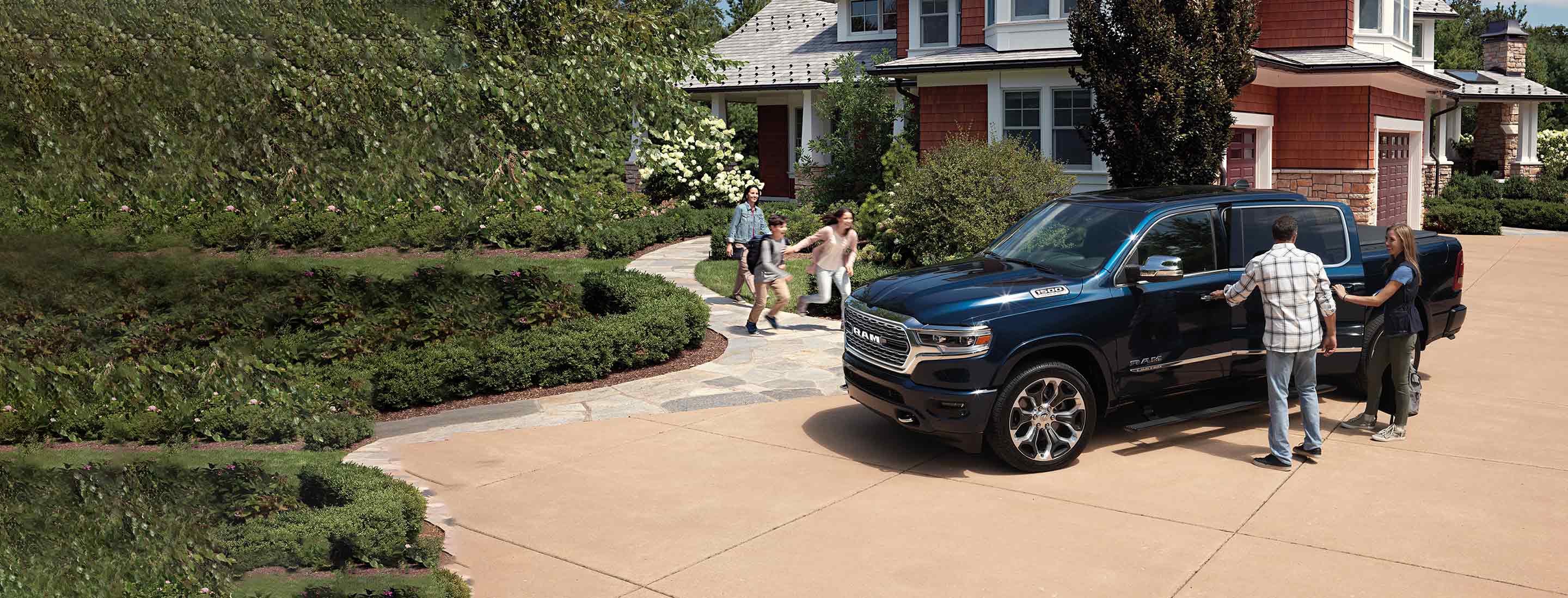 A family of five approaching a 2022 Ram 1500 Limited 4x4 with a Crew Cab and 5'7" box.