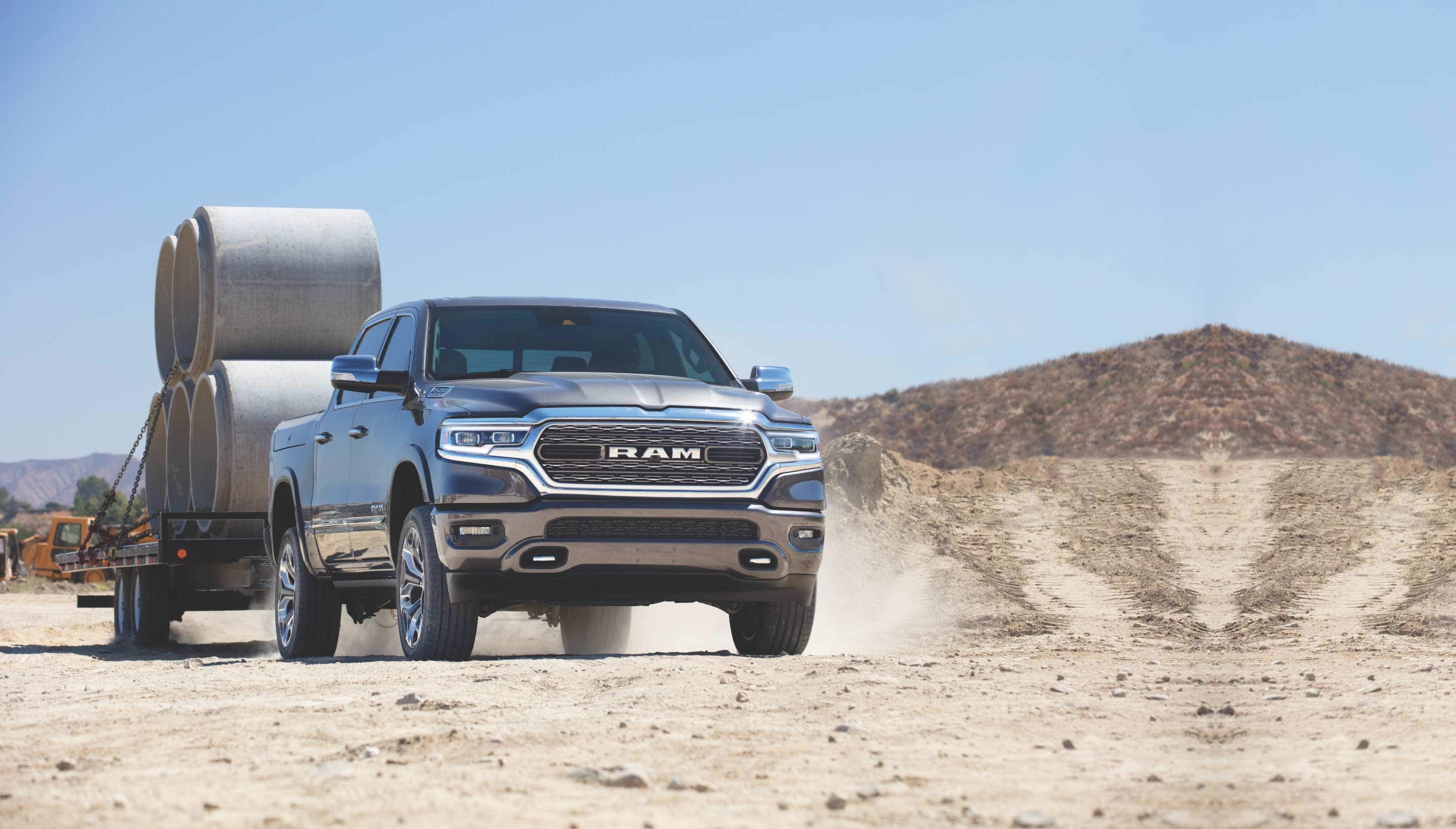 A 2022 Ram 1500 on a construction site towing a trailer stacked with concrete forms.