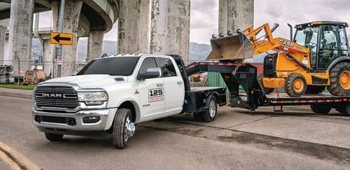 Ram Chassis Cab Towing A Construction Vehicle On A Flat Bed