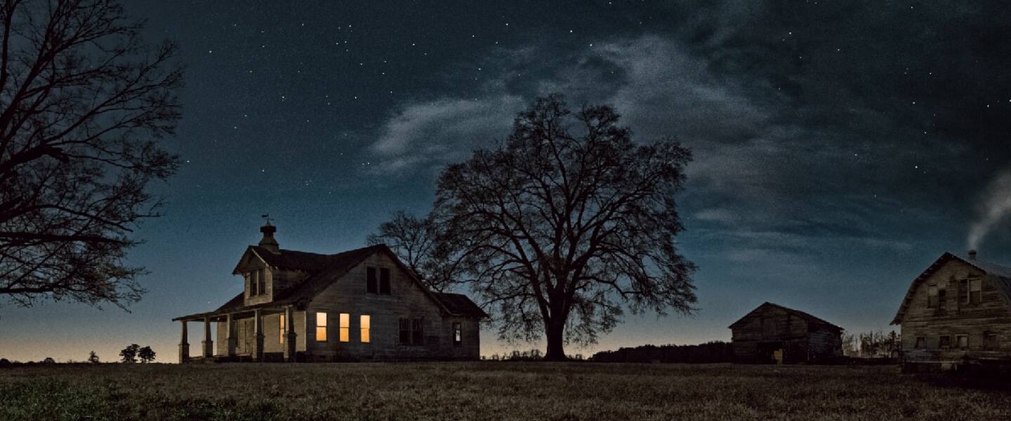 A farmhouse and outbuildings at dusk