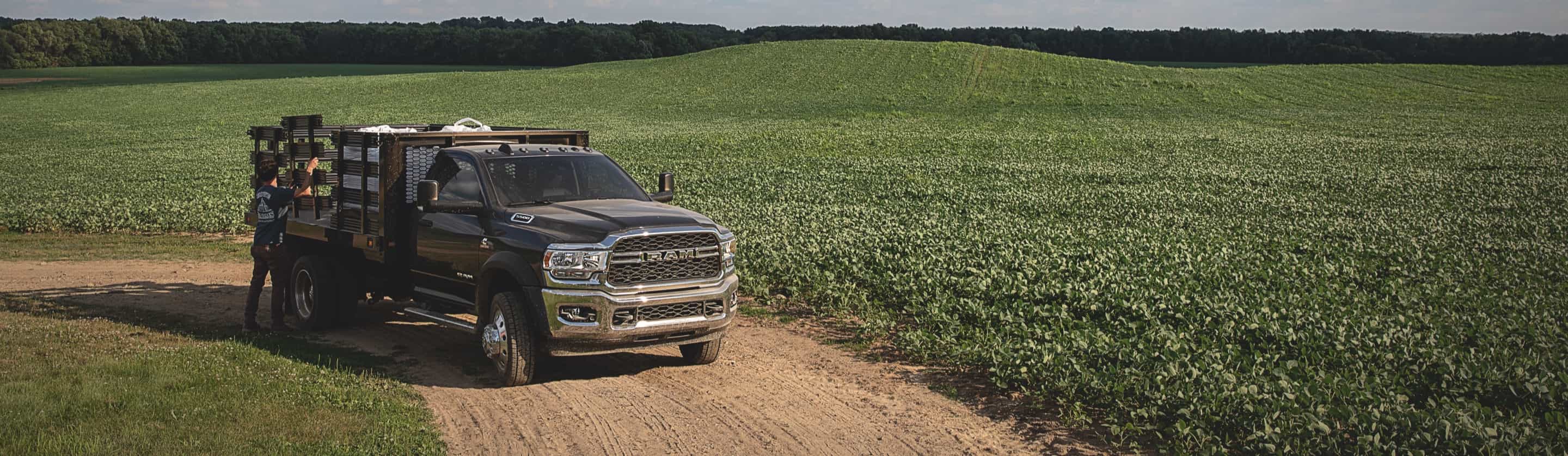 A 2019 Ram Chassis Cab with a stake upfit holding several large boxes, parked in a field.