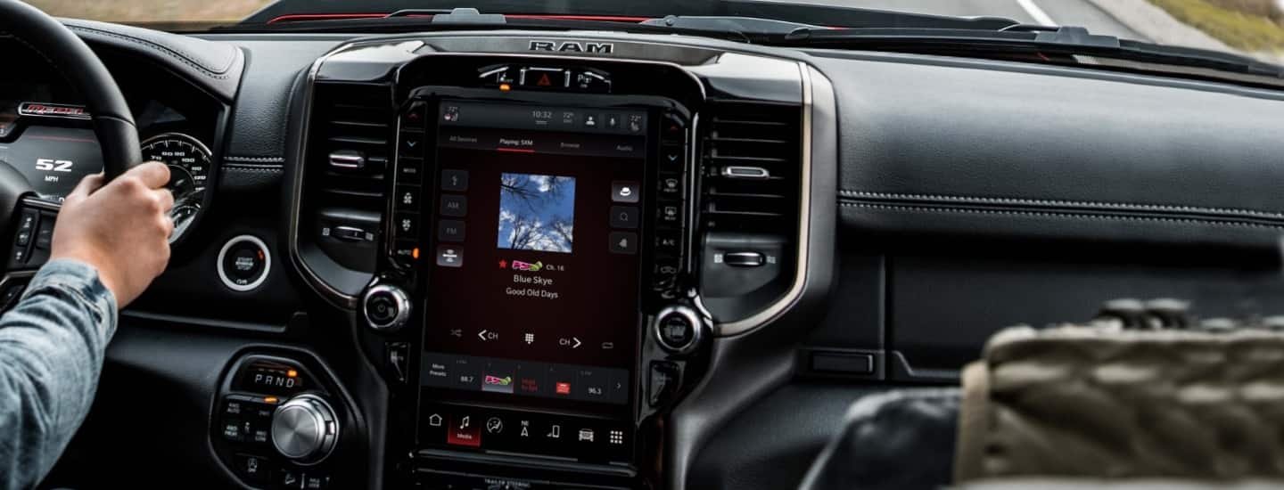 The touchscreen inside a 2022 Ram truck, displaying the song title and artist for the track currently being played through the Uconnect system.