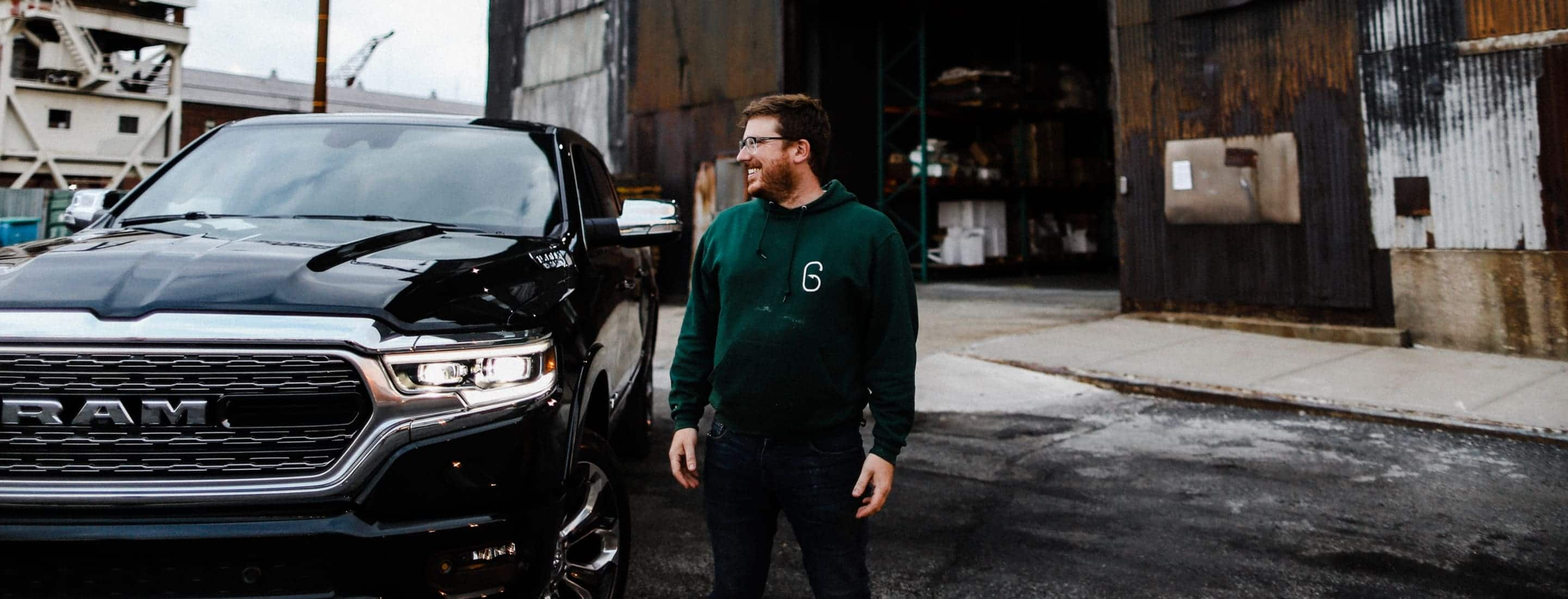 A man smiling broadly as he stands next to his 2019 Ram 1500 Limited.