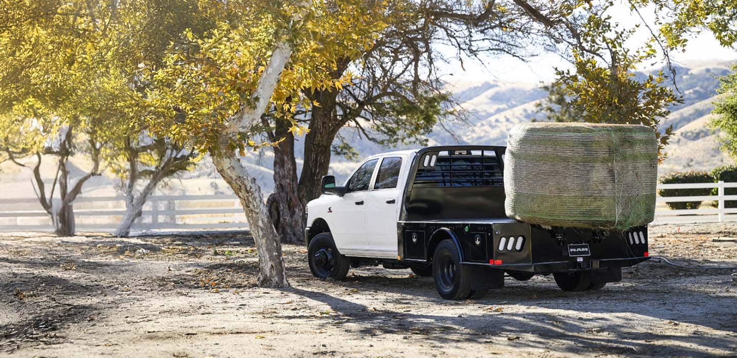 A Ram Chassis Cab truck with a large hay bale loaded into the cargo bed.