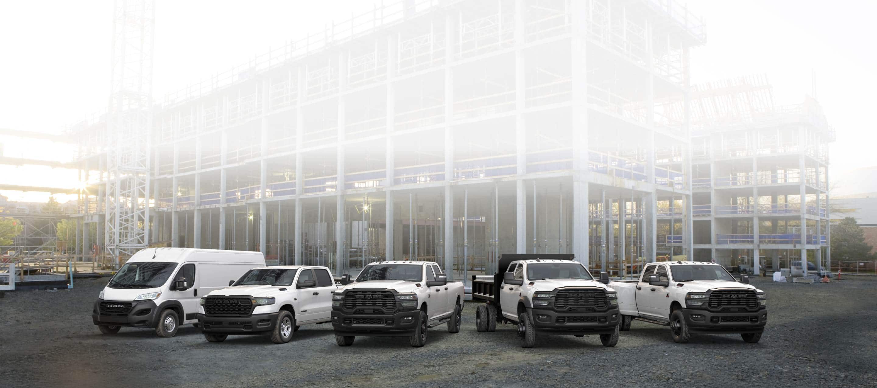 A lineup of 2026 Ram trucks and vans, all in white at a commercial construction site. From left to right: a Ram ProMaster 3500 Tradesman High Roof Cargo Van, a Ram 1500 Tradesman 4x4 Crew Cab, a Ram 2500 Tradesman 4x4 Crew Cab, a Ram 3500 Tradesman Crew Cab Chassis Cab with a dump body upfit and a Ram 3500 Tradesman 4x4 Crew Cab.