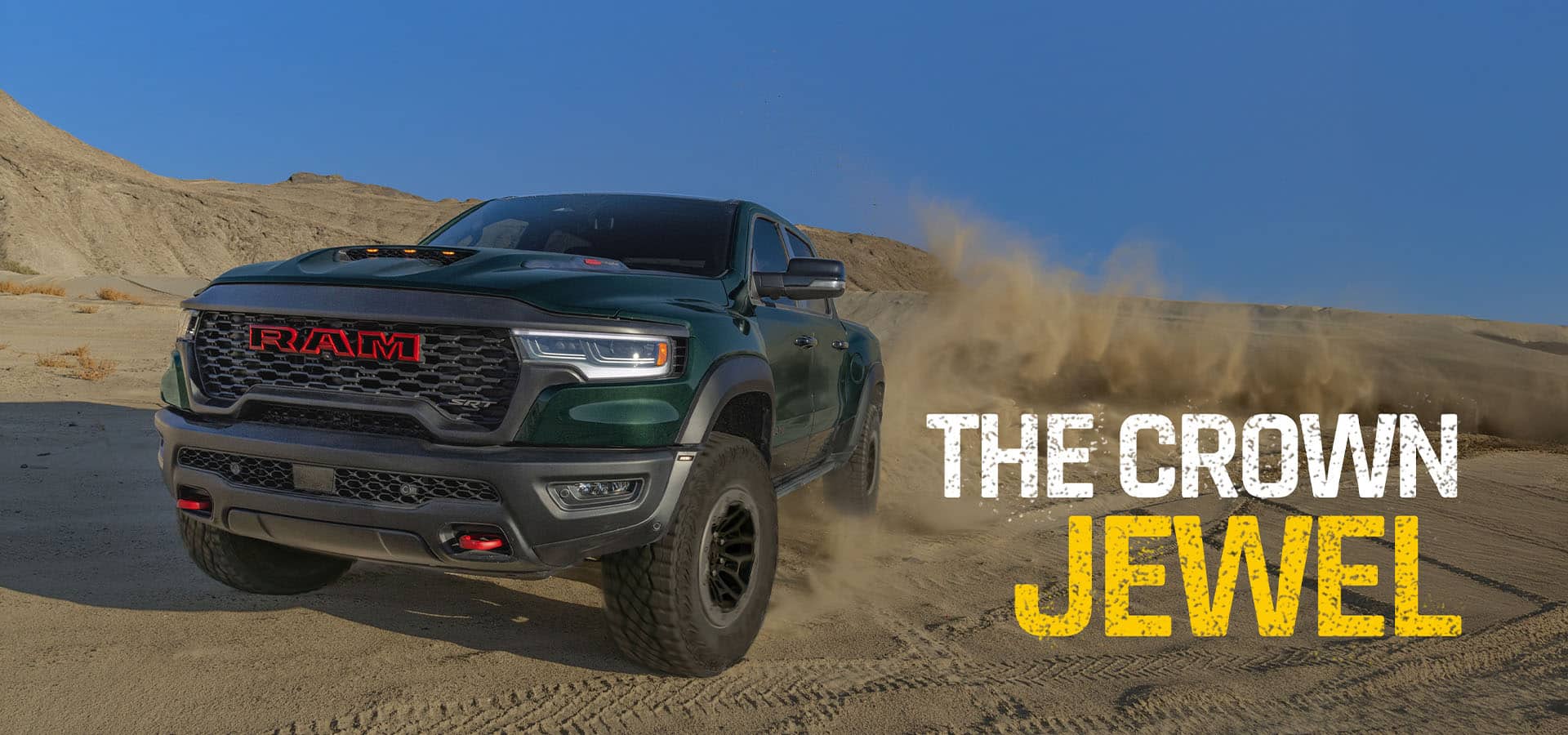 A green 2027 Ram 1500 TRX SRT 4x4 Crew Cab traveling through the desert, kicking up sand as it goes. The Crown Jewel.