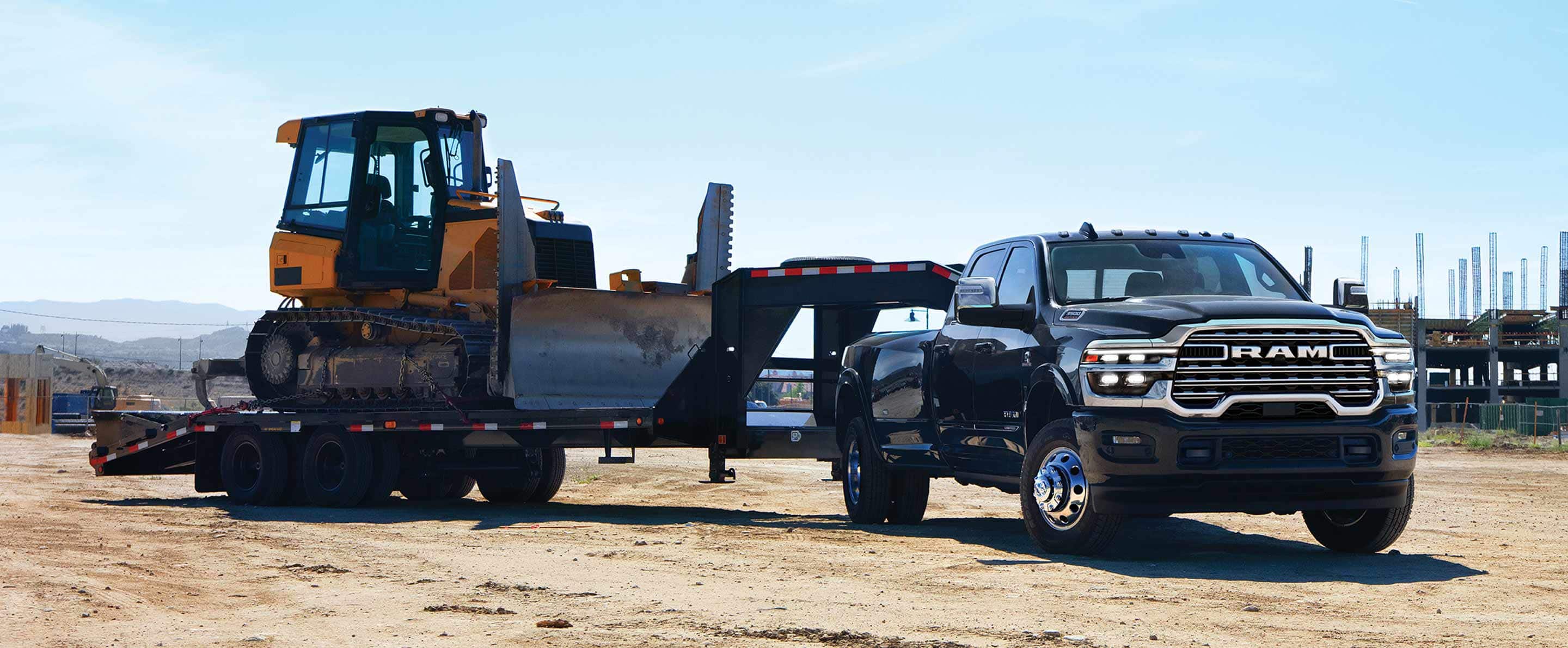 A black 2025 Ram 3500 Limited Longhorn Crew Cab towing a fifth-wheel flatbed trailer with an excavator on it.