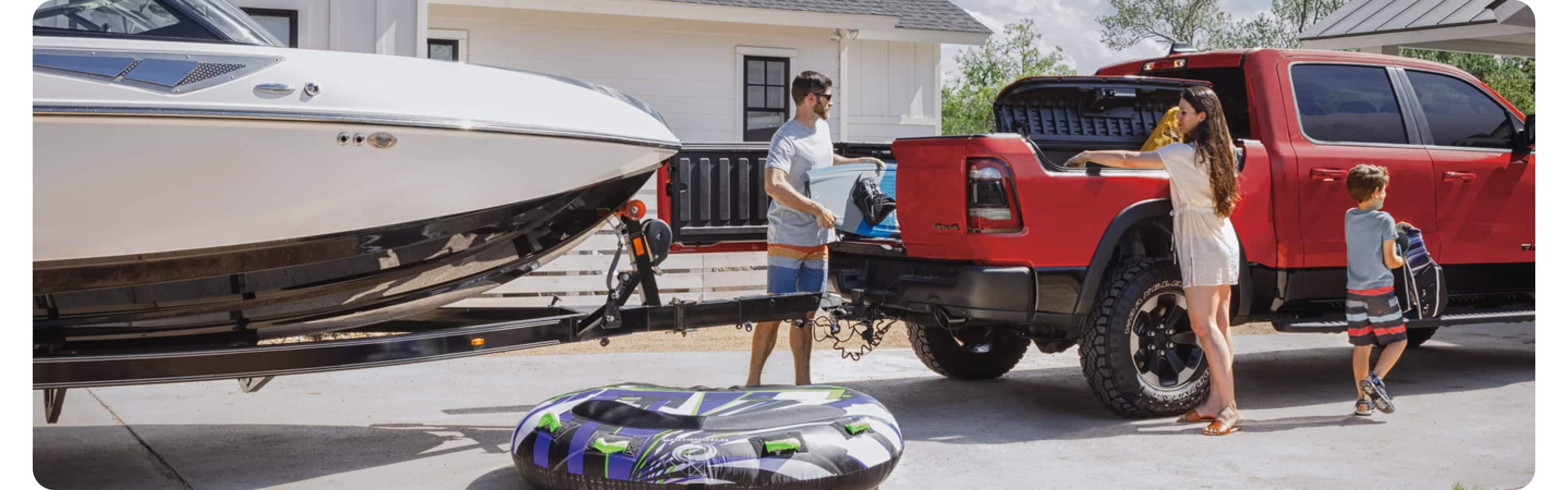 A family unloading a 2021 Ram 1500 with one door of its multifunction tailgate open, unimpeded by the boat the truck is towing.