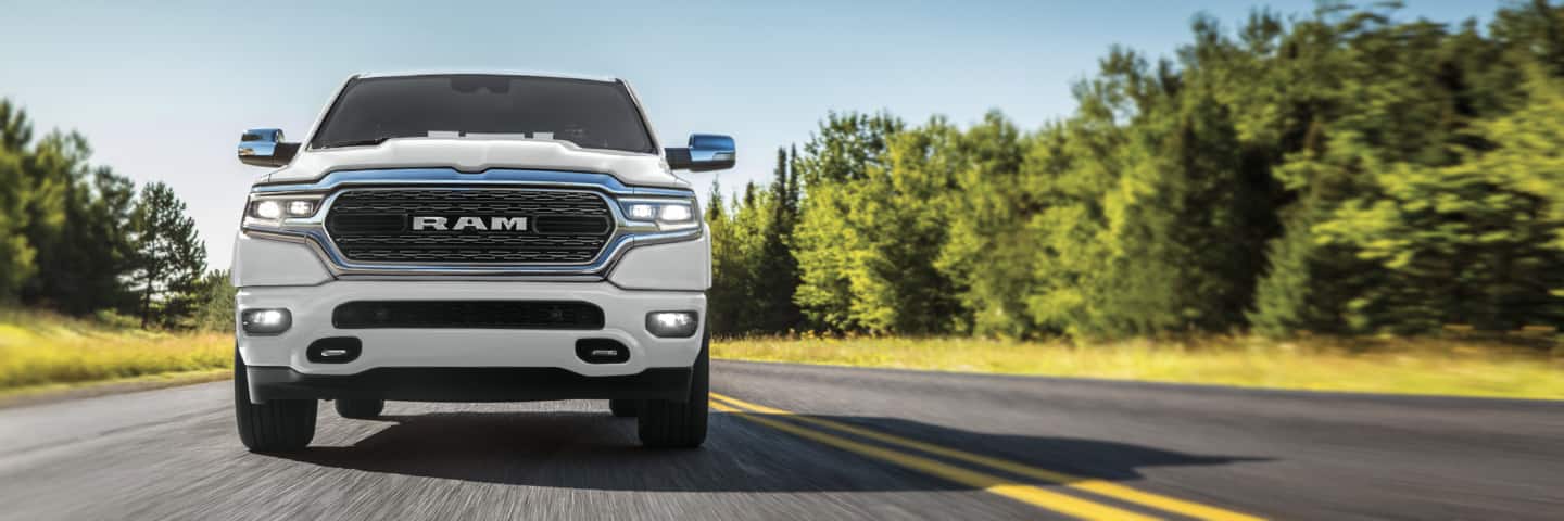 The 2022 Ram 1500 being driven on a road through the woods.